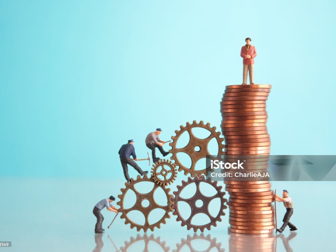 Miniature businessman on top of a pile of coins with construction workers, leadership, success concept